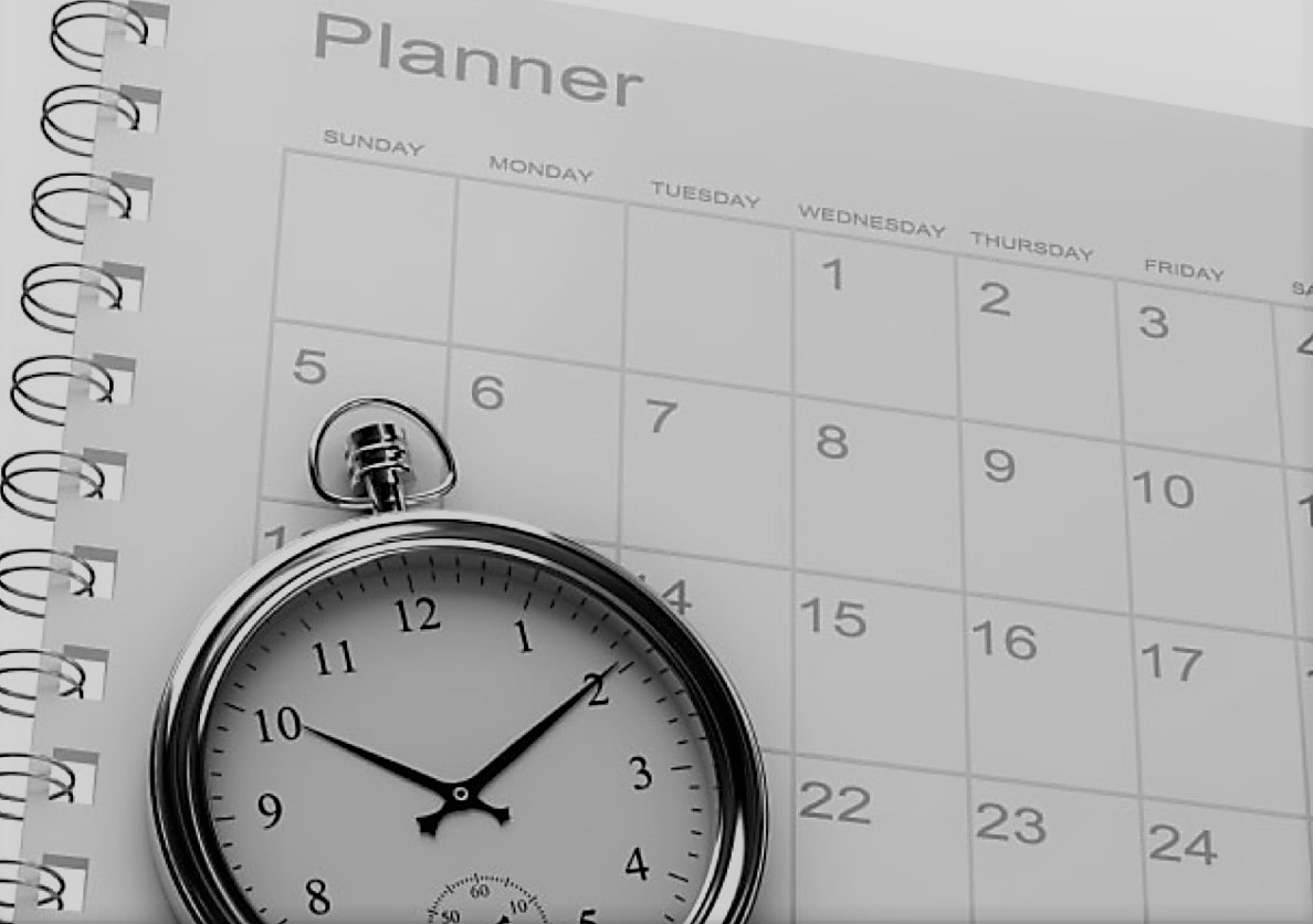 pocketwatch sitting on top of an open monthly planner
